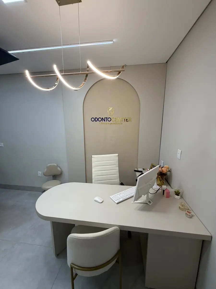 Sala de atendimento clara da Odonto Centter, com a marca iluminada na parede
