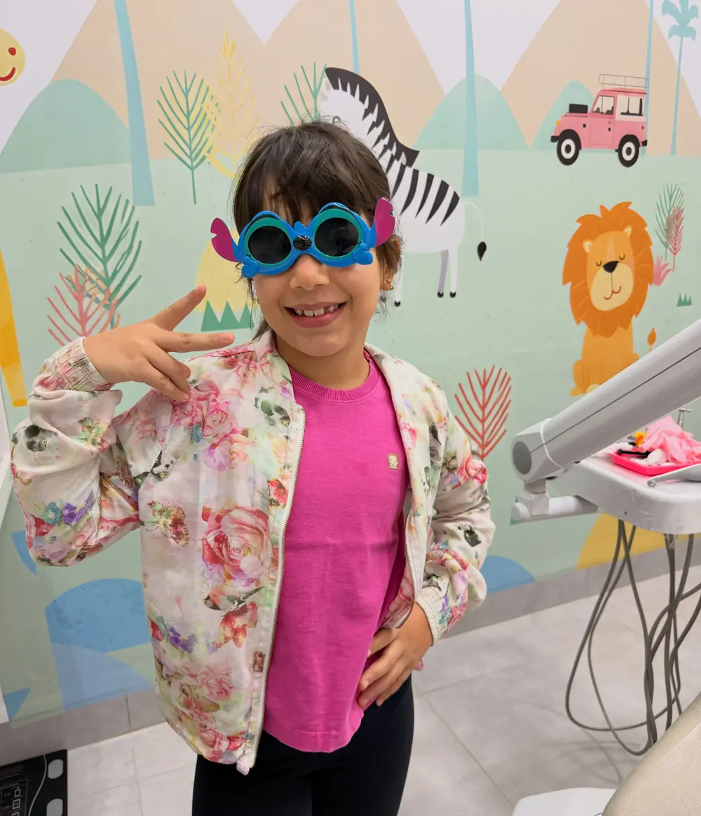 Criança sorrindo com óculos divertidos no consultório lúdico da Odonto Centter